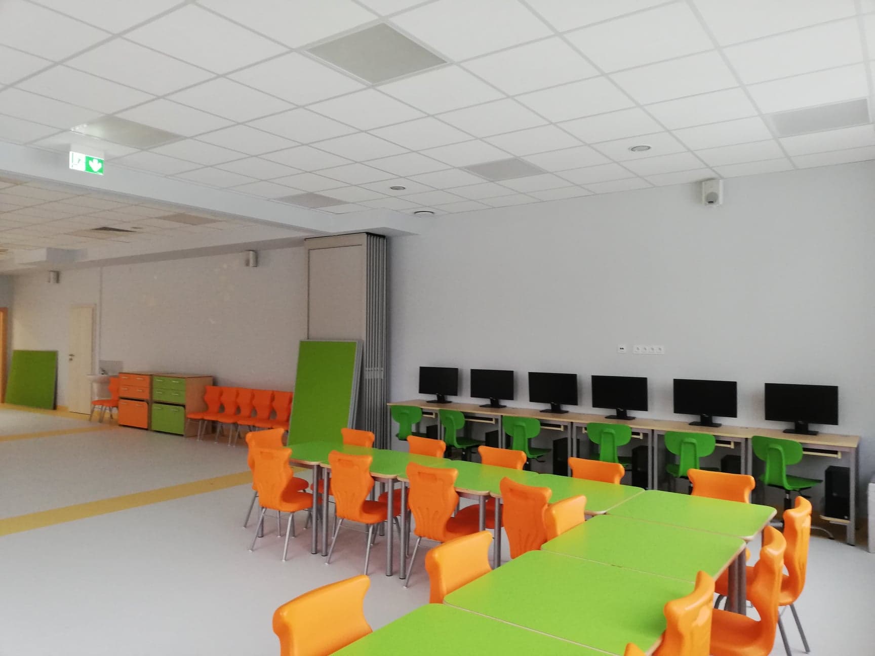 nowa świetlica szkolna z kolorowymi stolikami i stanowiskami komputerowymi